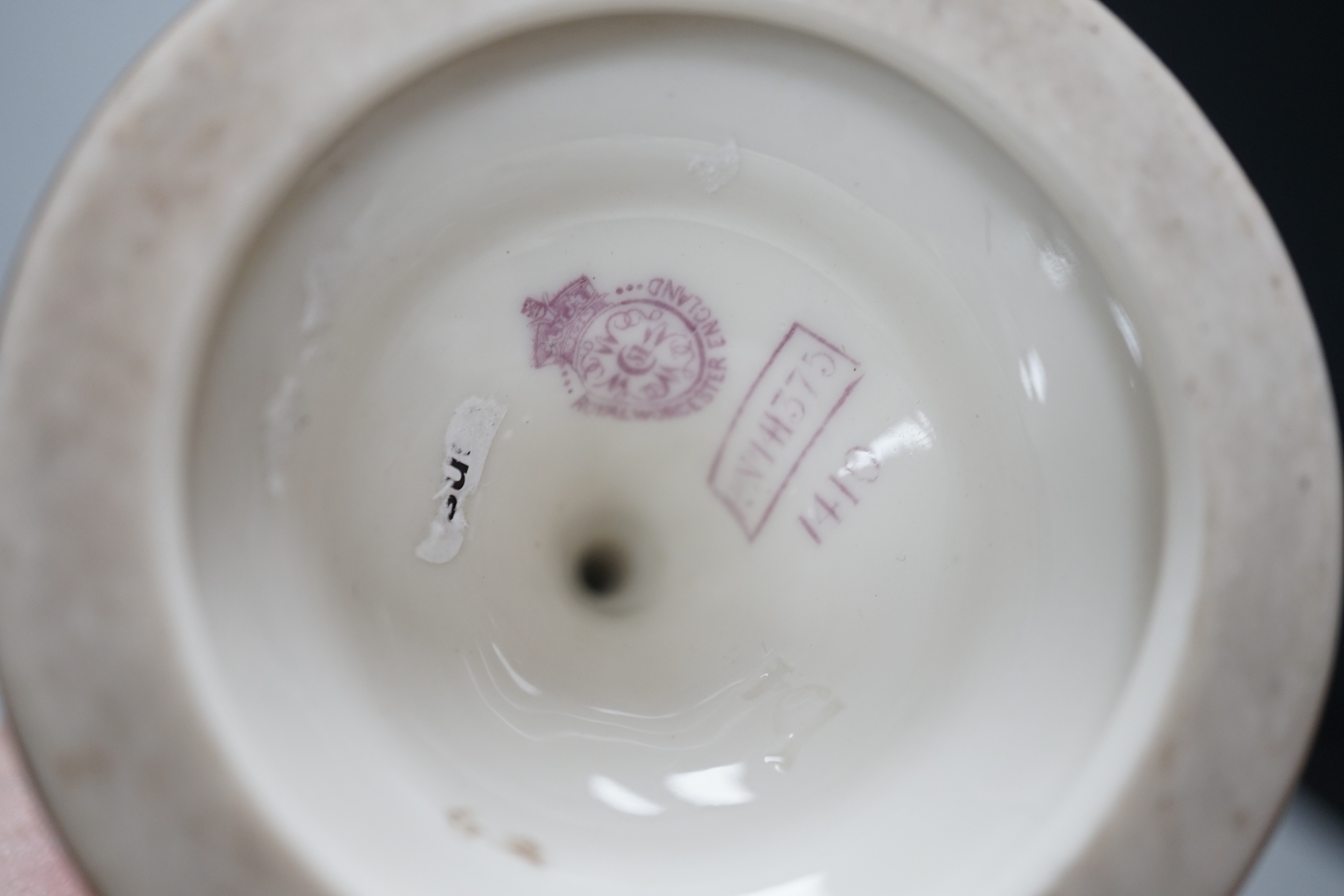 Three Royal Worcester pedestal vases, each of ovoid form and supported on circular pedestal feet, two are decorated with flowers and thistles, the other depicting a rural landscape within a gilt foliate C scroll cartouch